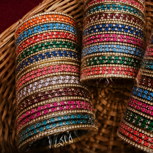 Three stacked bangles covered in colorful rhinestones, displayed inside a woven wicker basket.