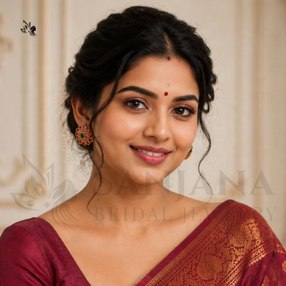 A woman wearing ornate gold and red traditional earrings, styled in a maroon saree, with a faint 'Sujana Bridal Jewelry' watermark across the image.