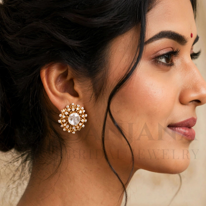 A close-up side profile of a woman wearing a large gold-toned floral stud earring with a clear central stone and small surrounding stones. The image includes a faint watermark reading 'HARI BRIDAL JEWELRY'.