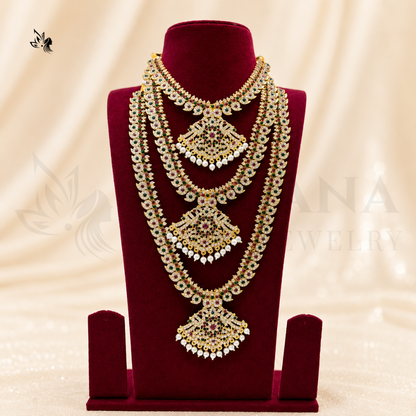 A gold-toned multi-strand necklace with intricate stone detailing, displayed on a dark red velvet jewelry bust against a cream satin background.