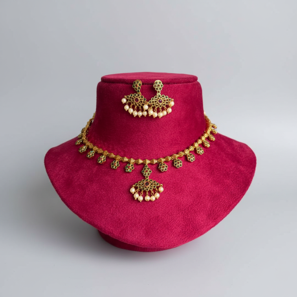Gold-toned traditional Indian jewelry set including a necklace, earrings, and a matching hair ornament, displayed on a magenta velvet jewelry bust against a light gray background.